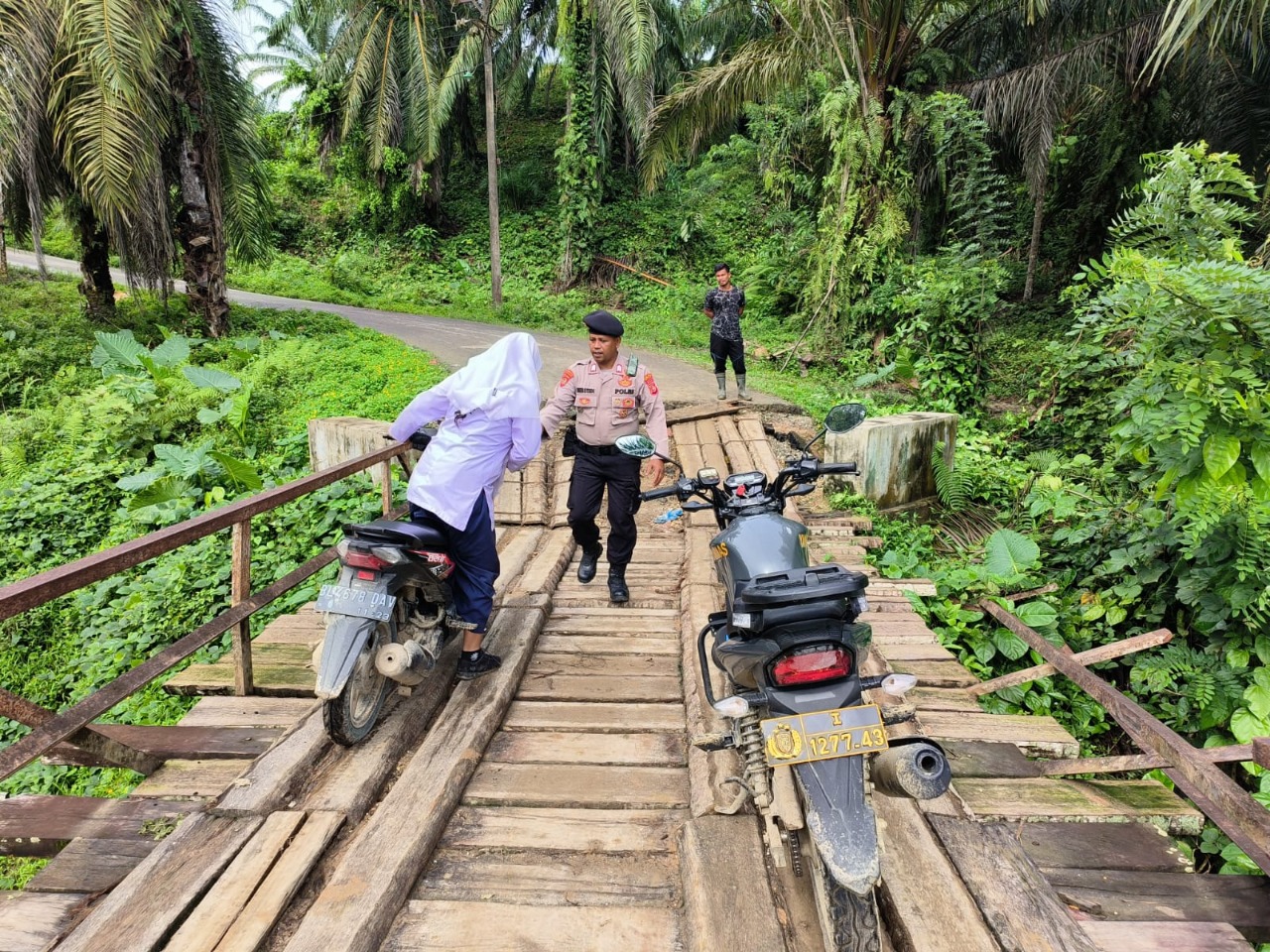 EFEK JEMBATAN RUSAK –  ANGGOTA POLSEK BANDA ALAM TURUN MEMBANTU WARGA