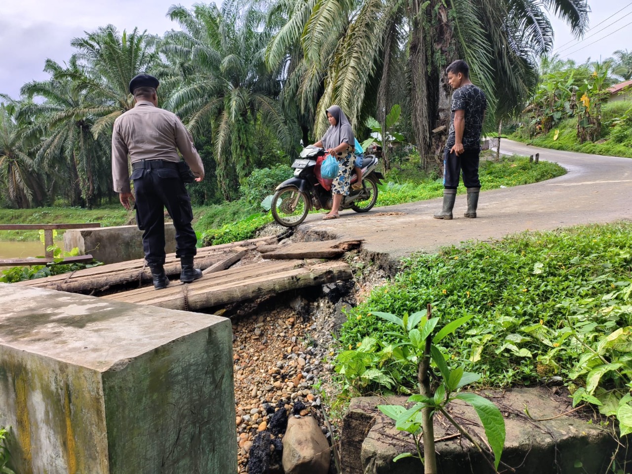 EFEK JEMBATAN RUSAK –  PERSONEL POLSEK BANDA ALAM TURUN MEMBANTU WARGA