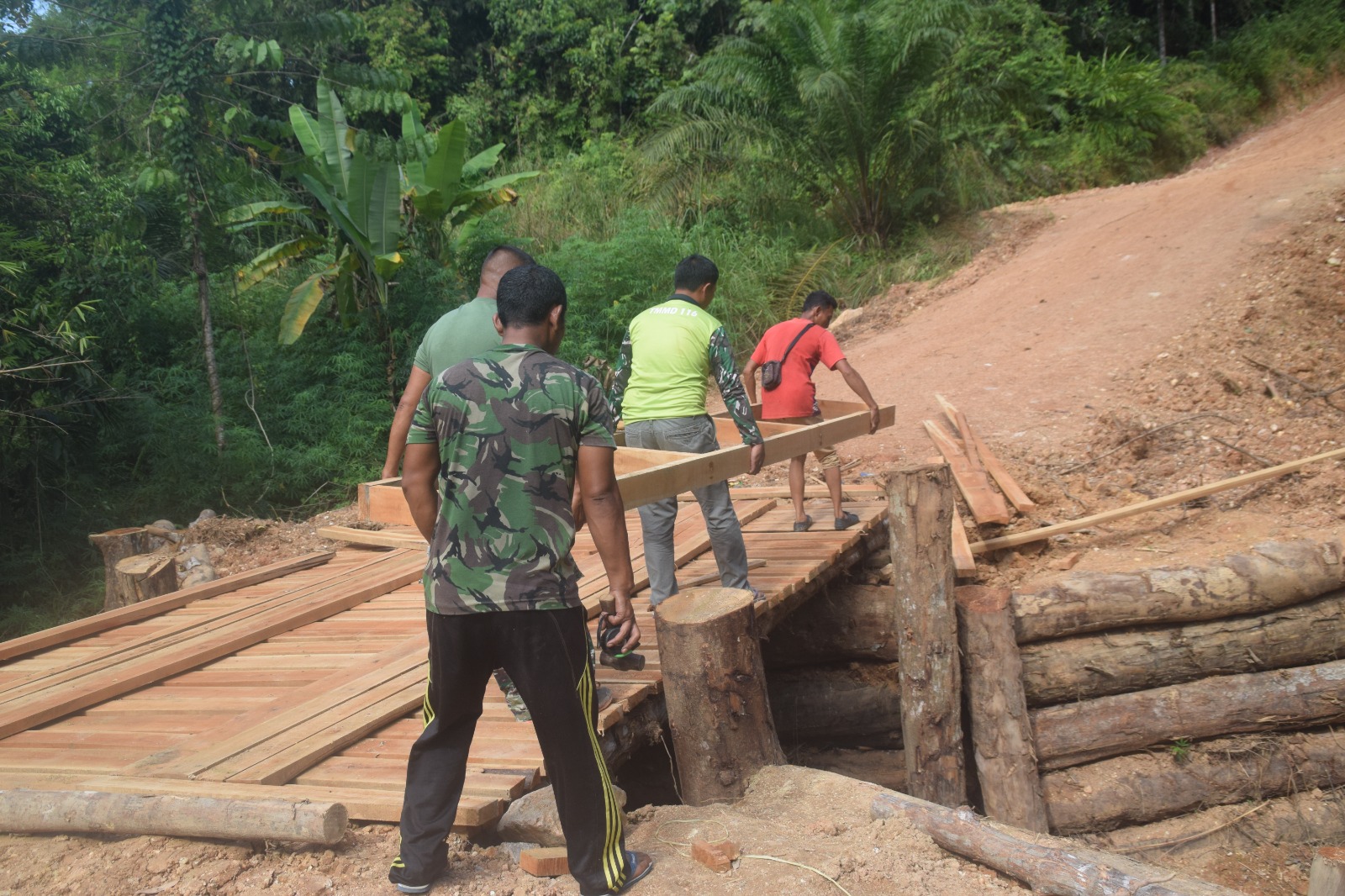Anggota Satgas TMMD 122 Kodim 0420/Sarko terus melanjutkan pekerjaan jembatan darurat di Desa Bedeng Rejo menuju desa Sungai Putih
