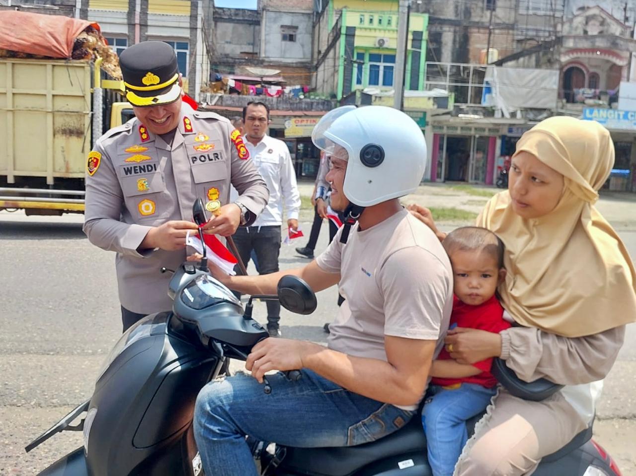 Sambut HUT Ke-80 RI, Kapolres Sarolangun didampingi Ketua Bhayangkari Bagikan Langsung Bendera Merah Putih ke Warga Singkut
